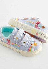 Svetle modré plátěné tenisky se suchými zipy, zdobené barevným květinovým a zvířecím vyšíváním, duhovými akcenty a texturovanou bílou podrážkou.