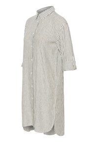 Longue chemise blanche à fines rayures verticales noires, boutonnée devant, col et manches retroussées avec pattes boutonnées.