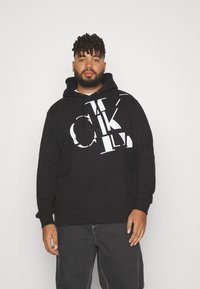 Black hoodie made of soft fabric, featuring large white block letters printed on the front. Drawstring hood and ribbed cuffs.