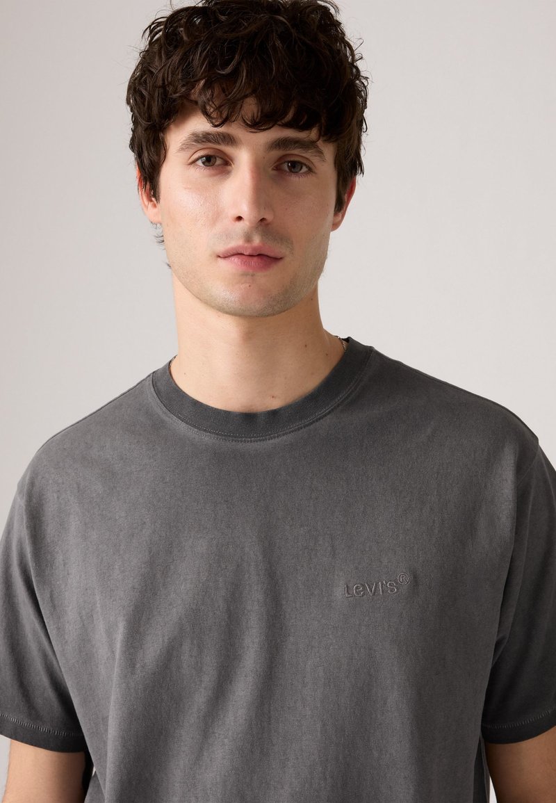 T-shirt en coton gris avec un col rond, présentant un logo Levi's brodé discret sur la poitrine et un fini en tissu doux et texturé.