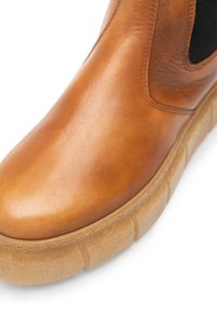 Brown leather ankle boot with elastic side panels, smooth texture, and a chunky beige sole. Features a subtle sheen and rounded toe design.