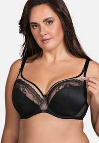 Sosten negro con una combinación de tela suave y encaje. Presenta aros, panel transparente, tirantes ajustables y un borde decorativo de encaje.