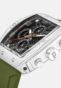 Orologio analogico argento e nero con quadrante nero texturizzato, dettagli arancioni e verdi, e cinturino in silicone verde. Presenta una cassa esagonale.