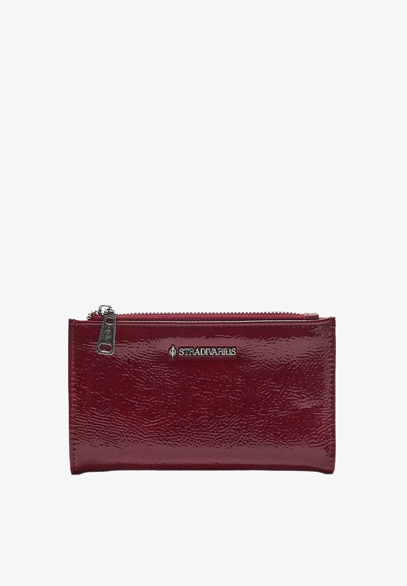 Burgunderfarbene Lackleder-Geldbörse mit glänzender Oberfläche, Reißverschluss und silbernem Logo-Akzent. Rechteckige Form mit strukturiertem Material.