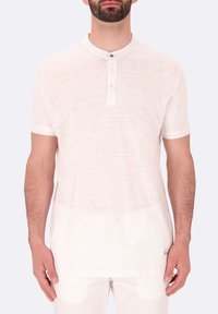 Maglietta henley bianca a maniche corte realizzata in un tessuto morbido e leggero, con una chiusura a bottoni e una texture sottile.