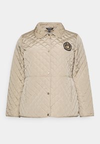 Béžová prošívaná bunda s dlouhými rukávy, kulatým límcem, předními patentkami, dvěma bočními kapsami a vyšitým znakem na hrudi.