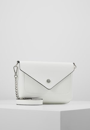 Sac bandoulière en cuir blanc avec rabat enveloppe, fermeture par bouton argenté et bandoulière amovible avec détail chaîne sur une surface blanche.