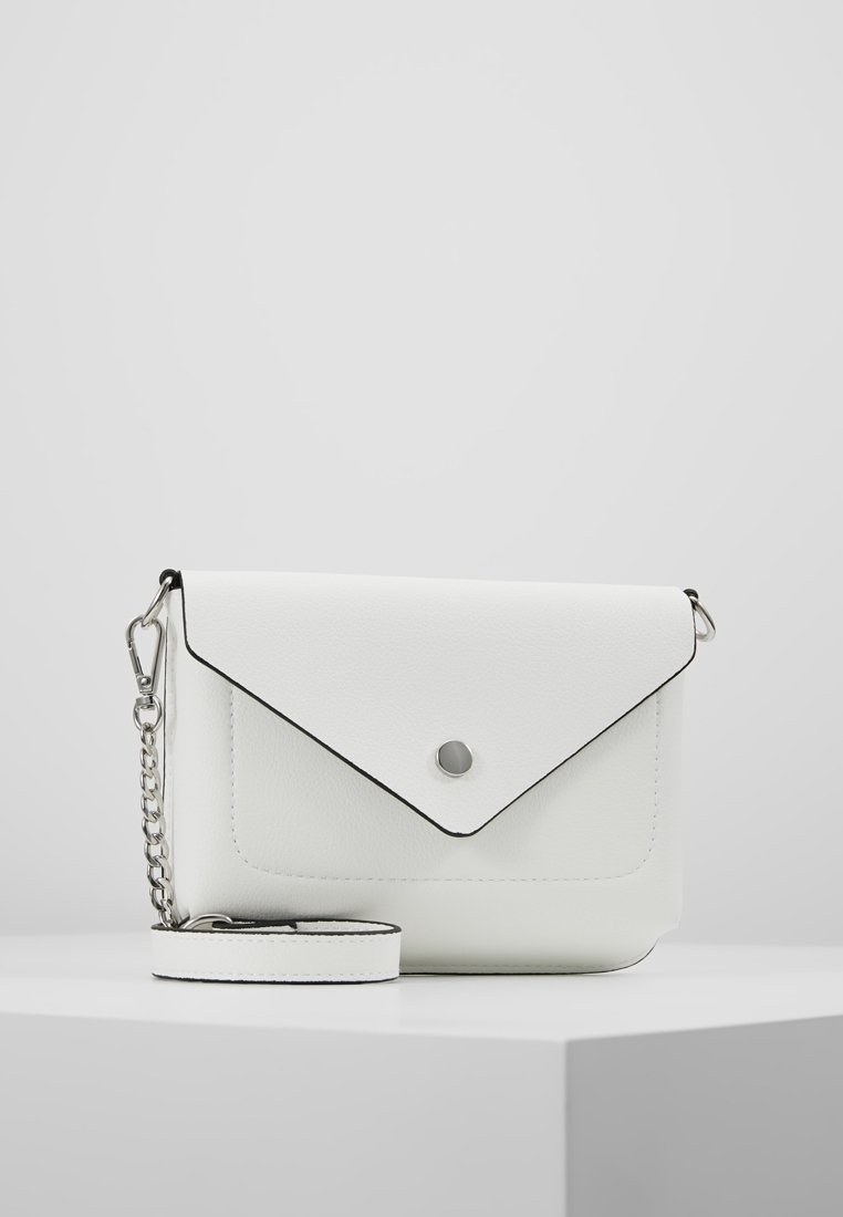 Sac bandoulière en cuir blanc avec rabat enveloppe, fermeture par bouton argenté et bandoulière amovible avec détail chaîne sur une surface blanche.