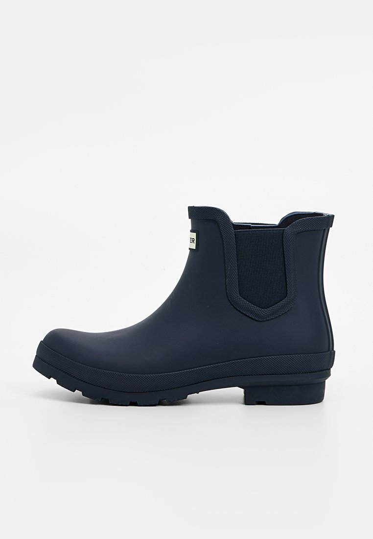 Marineblaue Gummistiefel mit elastischen seitlichen Einsätzen, strukturiertem Sohlenprofil und minimaler Markenkennzeichnung. Glatte Oberfläche mit abgerundetem Design der Zehenpartie.