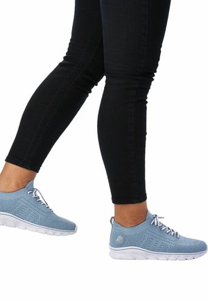 Blue mesh sneakers with white soles, featuring a perforated design and lace-up closure, worn with black skinny jeans.