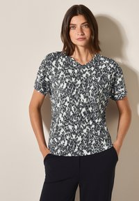 Korte mouwen V-hals top in zwart-wit abstract patroon, gemaakt van een luchtige stof en met een relaxte pasvorm. Getextureerde uitstraling met een lichte glans.