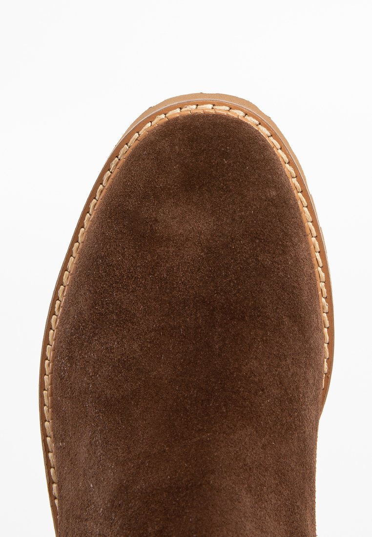 Bruine suede enkellaars met een ronde neus, voorzien van contrasterende stiksels langs de rand en een gladde, gestructureerde oppervlakte.