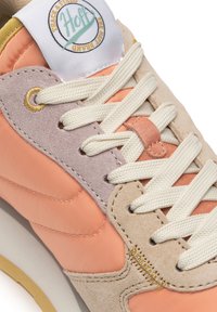 Sneakers wykonane z brzoskwiniowego i beżowego zamszu z kremowymi sznurówkami. Posiadają naszywkę z logo, kontrastujące faktury oraz akcent w kolorze żółtego złota w postaci oczka.