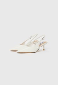 Valkoiset, kärjelliset slingback-kengät matalalla korolla. Silkkinen keinonahkamateriaali ja säädettävä nilkkaremmi soljella.