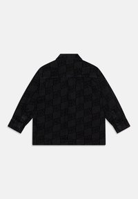 Giacca di jeans nera con motivo a scacchi stampato con la scritta "HUGO", colletto e maniche lunghe.