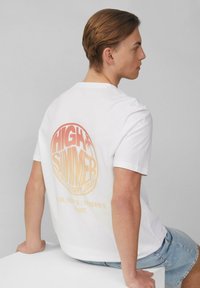 Witte katoenen T-shirt met een gradiënt oranje cirkelgrafiek op de achterkant met de tekst "HIGH SUMMER" en coördinaten, korte mouwen, ontspannen pasvorm.