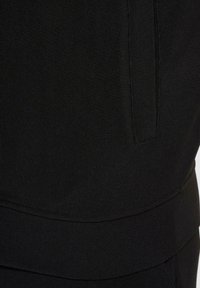 Sort sportstøj med ribbet tekstur, lagdelt design og diskrete syninger. Glat stof strækker sig til en talje.