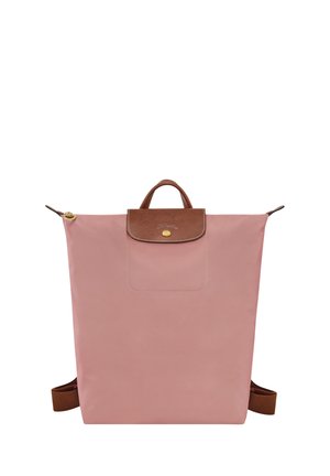 Pink fabric backpack with a brown leather top flap, gold snap closure, and adjustable brown straps. Features a front pocket. Simple rectangular design.