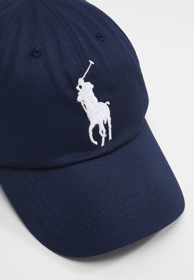Μπλέ καπέλο μπέιζμπολ με λευκό λογότυπο πολο σε κεντητό σχέδιο, καμπυλωτό γείσο και αεραγωγούς. Φτιαγμένο από υφασμάτινη ντεκολτέ για αυξημένη αντοχή.