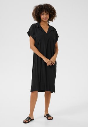 Schwarzes Kleid mit einem Kragen-Ausschnitt, kurzen Ärmeln und Spitzenbesatz. Verfügt über eine lockere Passform mit zwei vorderen Taschen und einem knielangen Saum.