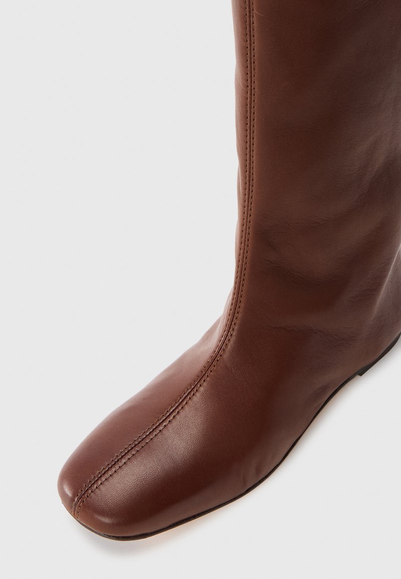 Bruine leren kniehoge laars met een ronde neus, een gladde textuur, subtiele stikdetails en een slanke silhouette.