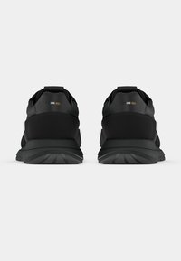 Chaussures de sport noires avec une tige texturée et une semelle en caoutchouc, dotées d'un talon rembourré et d'un design simple. Aucun logo ou ornement visible.