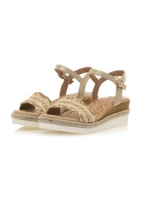 Sandalias de cuña con correas trenzadas doradas y una plantilla marrón. Presentan una plataforma de yute trenzado y un hebilla ajustable en el tobillo. Suela crema.