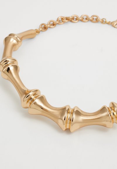 Gold-tone necklace featuring alternating smooth and ridged cylindrical shapes, connected by a chain, with a polished, reflective surface.
