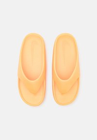 Narancssárga gumiból készült csúszó szandál, texturált talpbetéttel és puha felső pánttal. A talpbetéten Nike logó található.