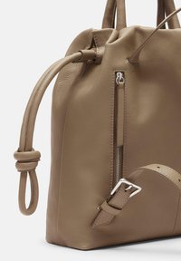 Brązowa skórzana torebka o textured wykończeniu, z boczną kieszenią na zamek błyskawiczny, węzłowymi uchwytami oraz detalem klamry na pasku.