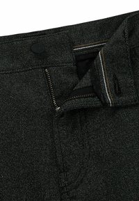Pantalon en denim noir avec des détails en fil argenté, fermeture éclair et bouton noir. Il présente une doublure en tissu à motifs et des accents de surpiqûre contrastants.