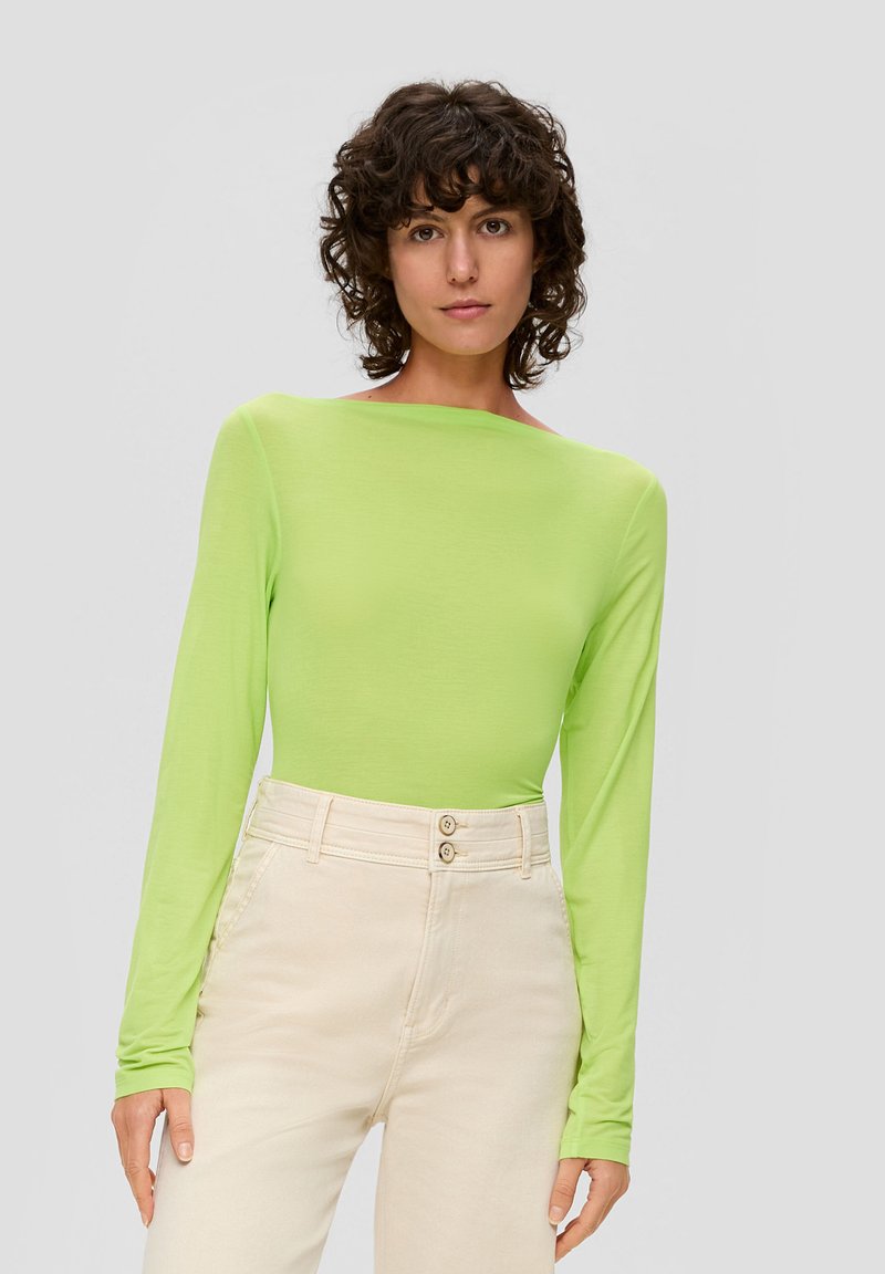 Langdurige mouw, fel limoen groene top van lichtgewicht materiaal, met een bootnek en een aansluitende vorm, gecombineerd met beige hoge taille broeken.