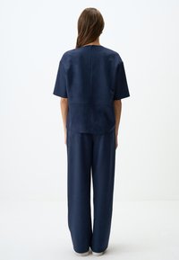 Completo coordinato di colore blu navy composto da una maglietta a maniche corte e pantaloni larghi, realizzato in un tessuto morbido e liscio con finitura opaca.