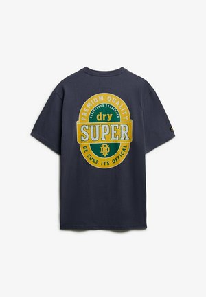 Marineblauwe T-shirt met een groot geel en groen cirkelvormig logo op de achterkant met de tekst "Premium Quality dry SUPER Wees Zeker Dat Het Officieel Is."