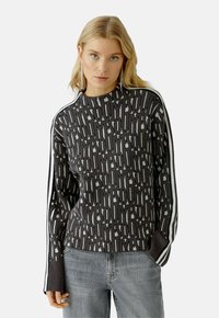 Donkergrijze gebreide trui met een geometrisch patroon in lichtgrijs. Ribgebreide boorden en zoom, met witte strepen langs de mouwen.