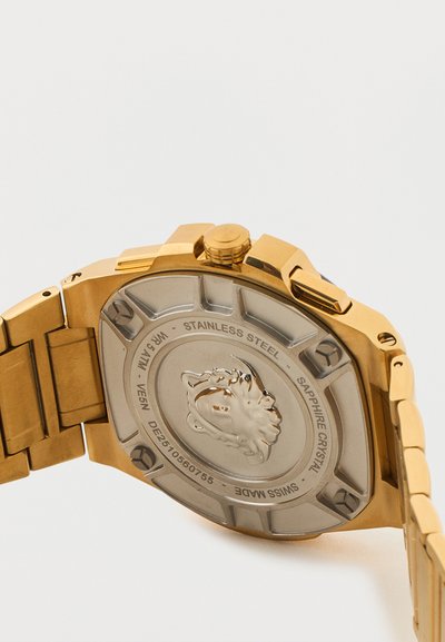 Aukso spalvos nerūdijančio plieno laikrodis žiūrint iš nugaros, matyti įgraviruotas liūto emblemą ir ženklinimai apie safyro kristalą, vandens atsparumą ir Šveicarijoje pagaminta.