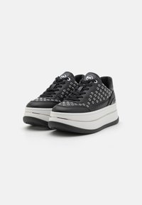 Sneaker in pelle nera con suola piatta bianca, dotate di grandi occhielli e lacci neri. Include un logo circolare sulla linguetta.