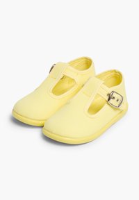 Scarpe in tela gialla con design a T-strap, caratterizzate da una fibbia in metallo e una suola in gomma flessibile. Texture liscia e stile minimalista.