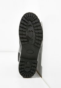 Černá pryžová podrážka s hlubokým vzorkem pro dobrý záběr, s kulatým tvarem a hladkou střední částí, vhodná pro různé terény.