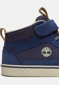 Botte de basket montante bleu marine en suède texturé, avec un col rembourré, une fermeture à crochet et boucle, et une semelle en caoutchouc clair avec un détail de logo.