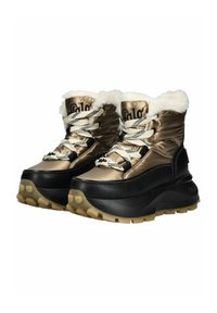 Botas con un upper metálico dorado, borde de piel sintética blanca y acentos de cuero negro. Suela gruesa y texturizada con agarraderas redondeadas.