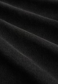 Tela de mezclilla negra con un ligero brillo, que presenta una textura visible y una superficie suave. El material es grueso con un patrón tejido.