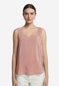 Ärmlös topp i ljusrosa genomskinlig tyg, med en bred rund halsringning och flödande siluett, matchad med vita högmidjade byxor.