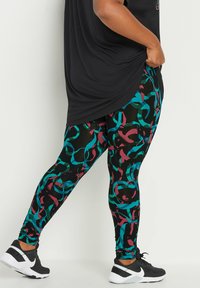 Leggings dengan dasar hitam yang memiliki pola abstrak berwarna teal, merah muda, dan hijau. Terbuat dari kain elastis, cocok dipadukan dengan sepatu olahraga.