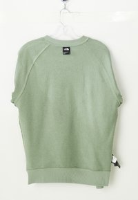 Sweatshirt vert clair avec un col rond à côtes et des manches courtes. Présente une étiquette en boucle au niveau du col et une étiquette tissée contrastante à l'ourlet.