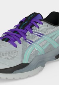 Ανοιχτό γκρι και μωβ αθλητικό παπούτσι ASICS με μωβ κορδόνια, μαύρη εσωτερική επένδυση και σχέδιο με ρίγες σε τιρκουάζ και μωβ στη πλευρά.