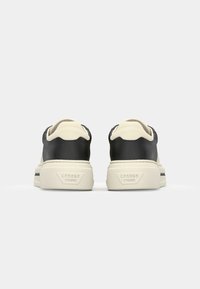 Sorte og kremfargede lær-sneakers med glatt tekstur, avrundede bakdeler og såle i hvit gummi med teksturert grep.