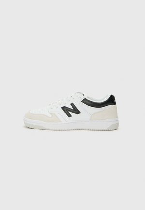 Białe sneakersy z czarnymi akcentami, wykonane ze skóry i zamszu, z perforowanymi detalami, fakturowaną podeszwą oraz logo po boku.