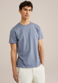 Tričko s krátkým rukávem a kulatým výstřihem v světle modré barvě z bavlny. Hladká textura, volný střih, s jednoduchým designem a bez vzorů či akcentů.