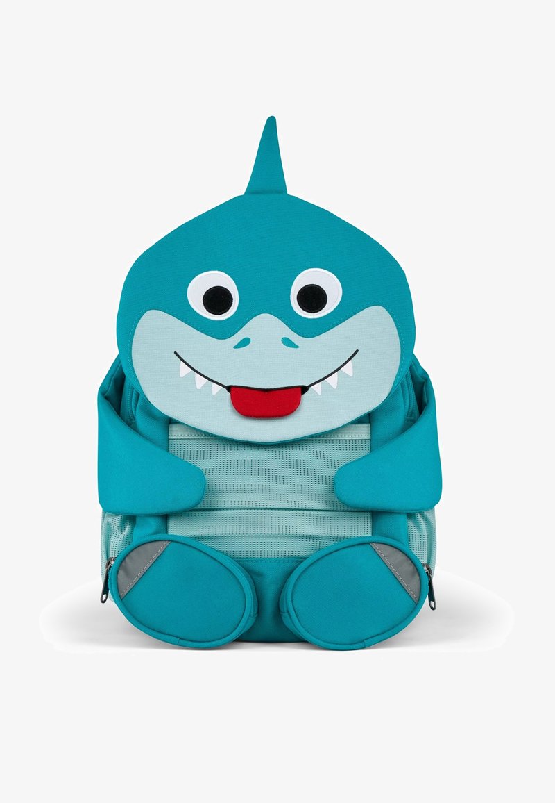 Türkisfarbener Rucksack in Form eines Hais mit großen Augen, einem lächelnden Mund und Stoffarmen. Verfügt über ein Netzrücken und abgerundete Bodenelemente.